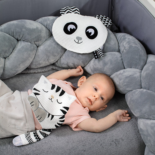 Dziecko leżące w łóżeczku z zabawką sensoryczną "Kitty Blink & Smile" od Babyono.