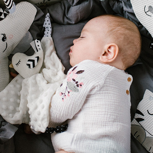 Dziecko śpiące w łóżeczku, obok przytulanka - kocyk "Little Birdie" od Babyono.
