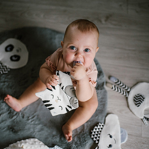 Dziecko bawiące się zabawką sensoryczną "Kitty Blink & Smile" od Babyono.