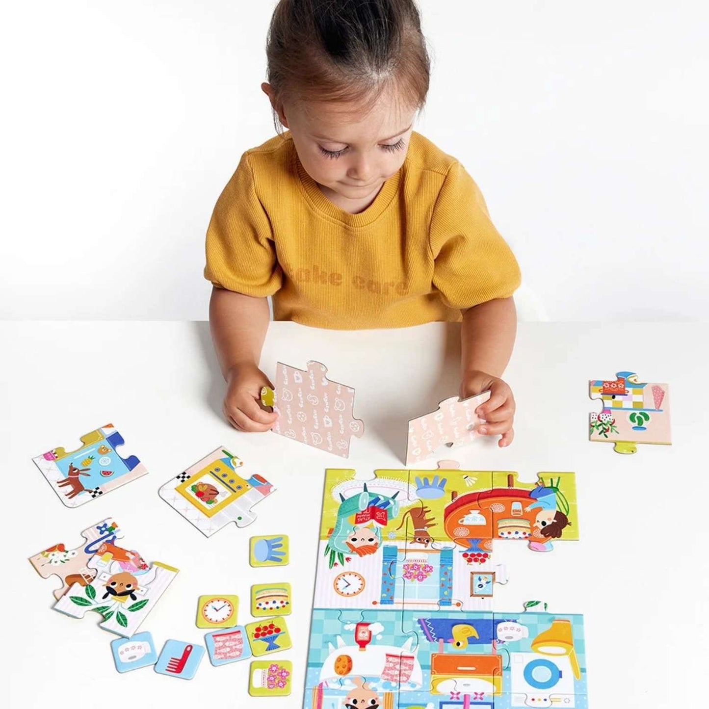 Elementy puzzli i obrazki do dokladania – edukacyjny zestaw CzuCzu Co robimy w domu – zbliżenie kolorowych elementów i dodatkowych obrazków.